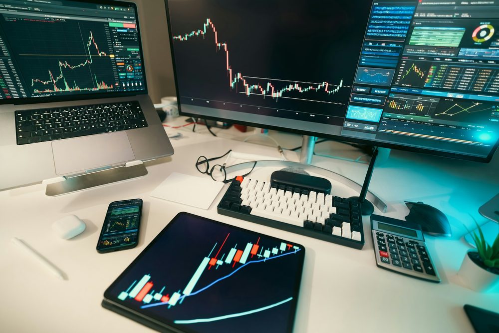 Trading desk with live charts on a monitor and a tablet